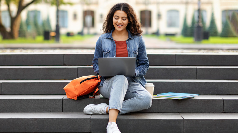 Woman sitting on steps at college doing homework