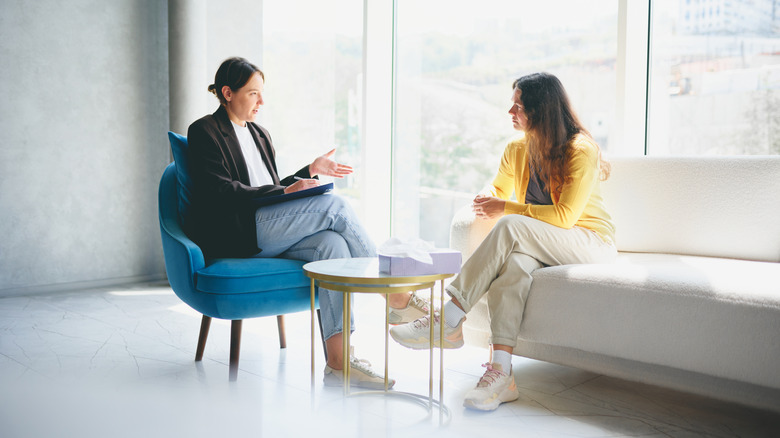 woman talking to female therapist beside bright window