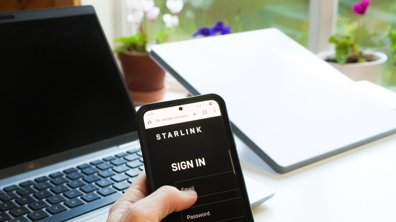 A person logging into their Starlink account on their phone with Starlink accessories in the background