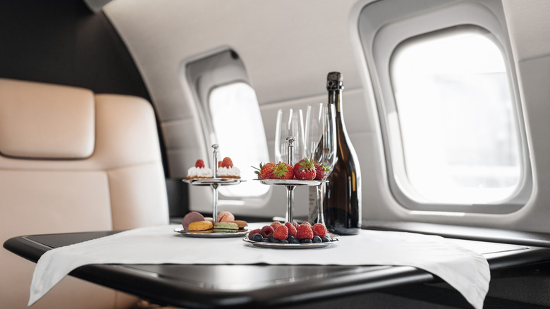 A Business Jet interior with some desserts and a bottle of champagne on the table