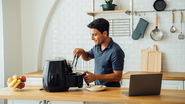man cooking in kitchen with air fryer