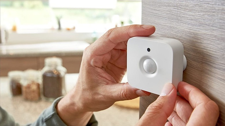 Person installing Philips Hue Smart Motion Sensor on wall