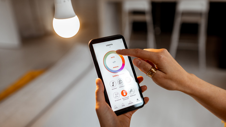 Woman controlling Philips Hue smart bulb with smartphone app
