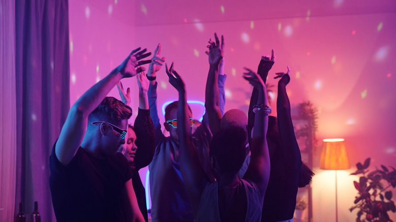 Group of friends dancing at a party with colored lighting