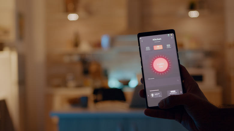 Man holding smartphone controlling kitchen smart lights