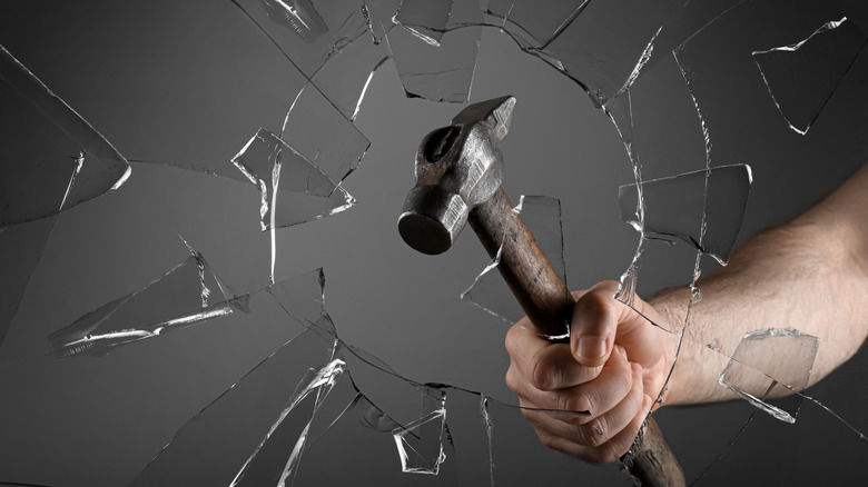 Man breaks glass with a hammer