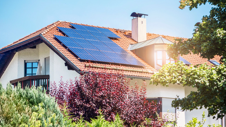 Old House with Solar Panels Station on Roof House with Green Garden