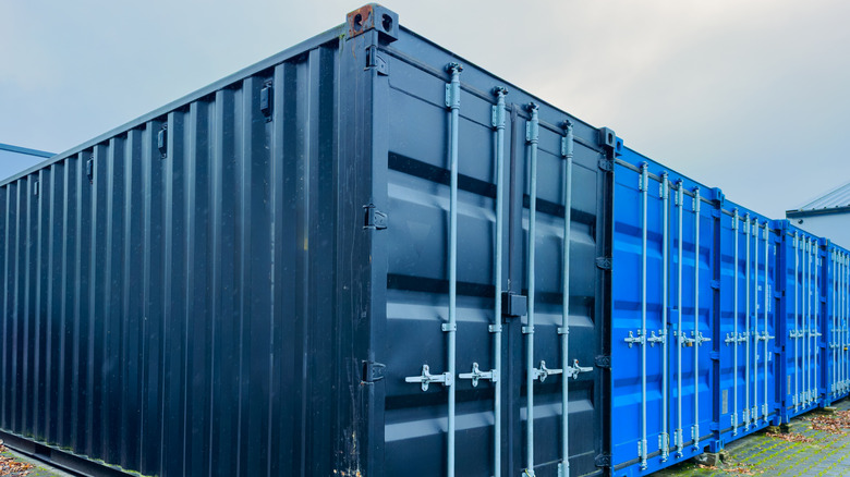 A row of vibrant shipping containers stands tall in a gravel area
