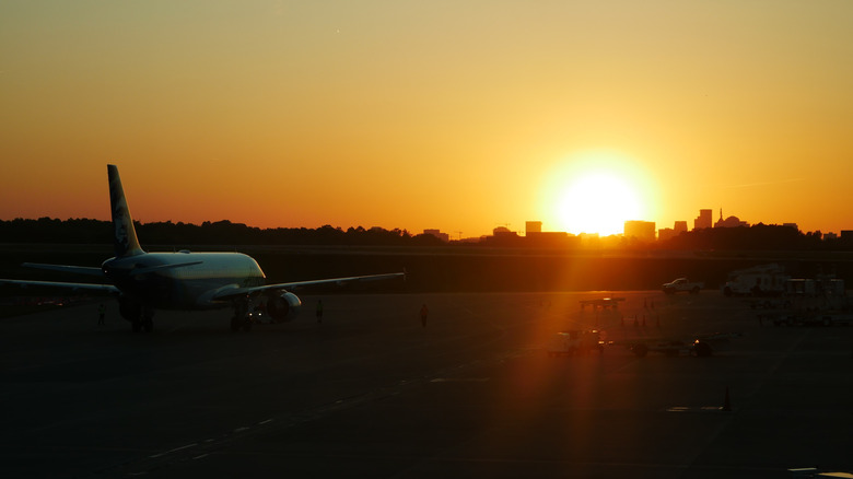 An airplane on a runway at sunset