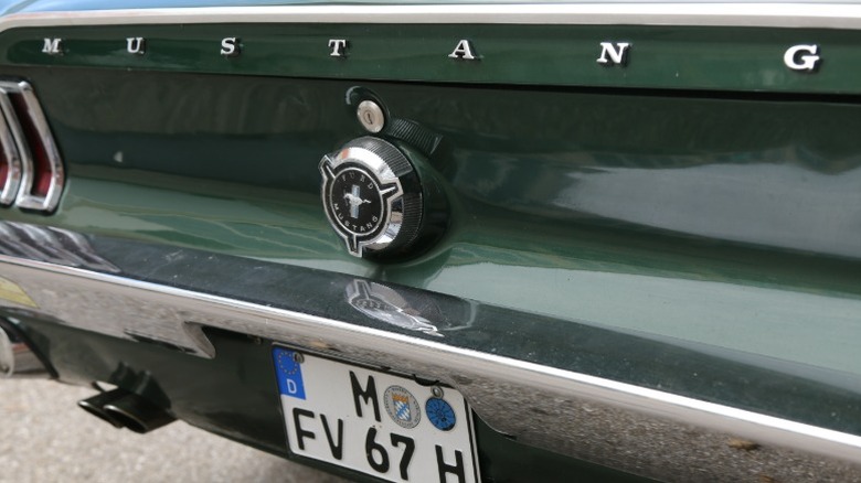 Close-up of Mustang logo and name on rear of green 1967 Ford Mustang