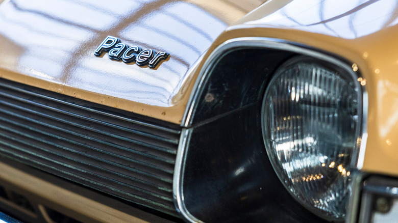 A close-up of the Pacer hood badge on the AMC pacer, headlight out of focus, cream exterior