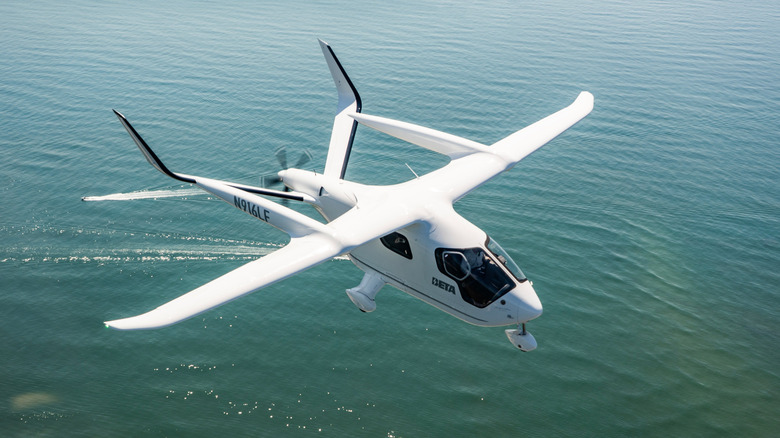 An electric plane made by BETA Technologies in the air over water
