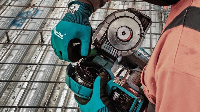 Worker inserting reel of 16 ga wire into Makita Rebar Tying Tool