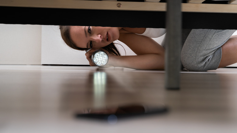 woman finding phone under bed