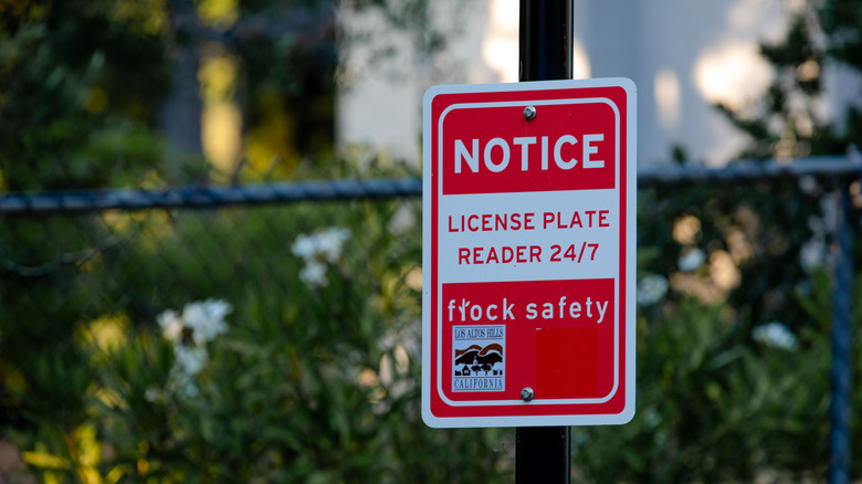 A red and white street sign warning drivers of the presence of an automatic license plate reading camera