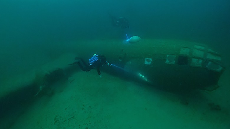 Two divers swimming around a submerged B-29 Superfortress in Lake Mead