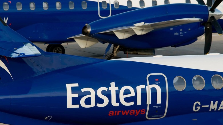 a pair of Eastern Airways jets wait on the runway