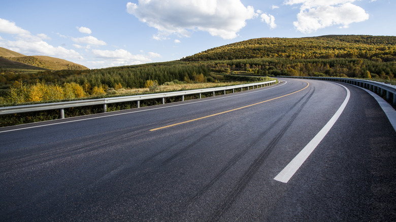 A long asphalt highway through grassy plains.