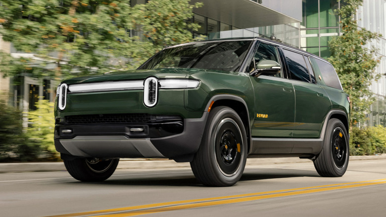 green Rivian R1S driving down urban street