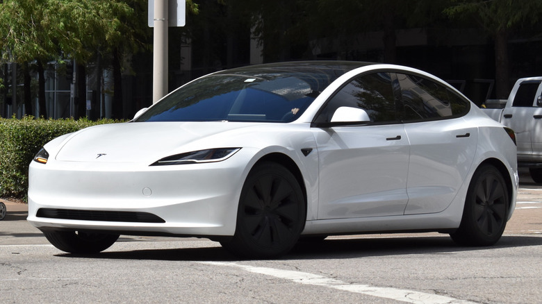 A white Tesla vehicle on a road.