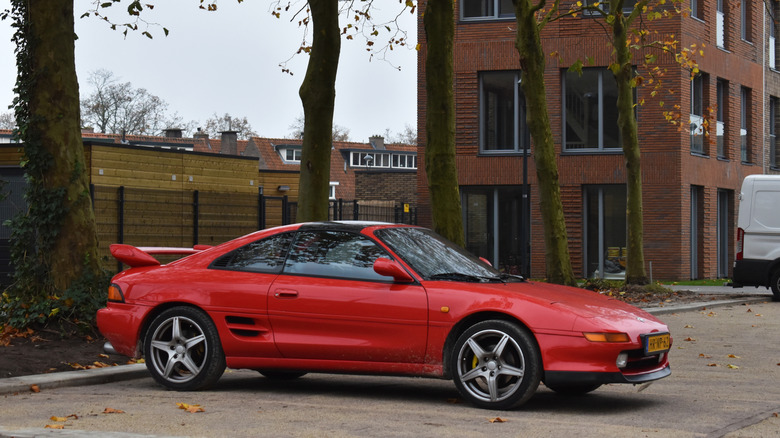 A second generation SW20 Toyota MR2 parked outside a brick building