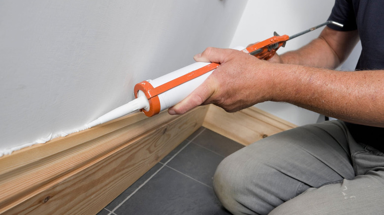 Man caulking wooden skirting in a new property
