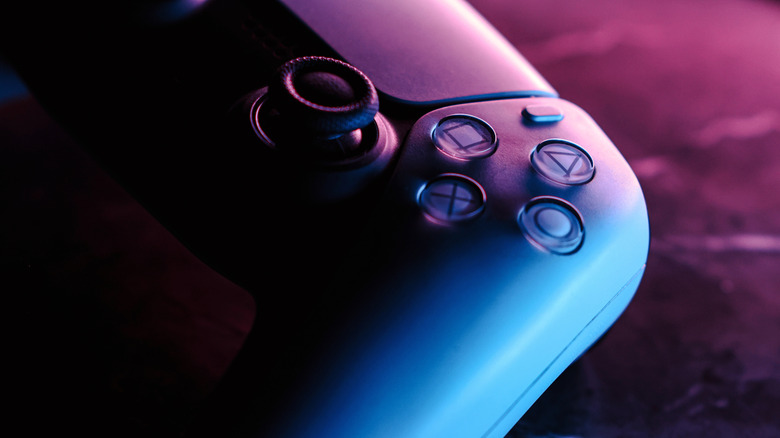 A PS5 controller under blue and purple mood lighting.