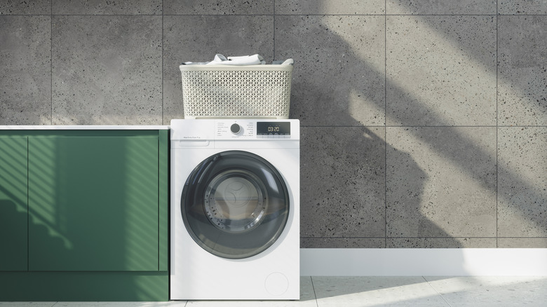 A washing machine with a laundry basket standing on the top.