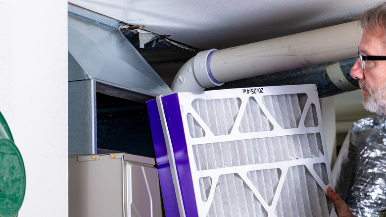 A person changing their furnace filter.