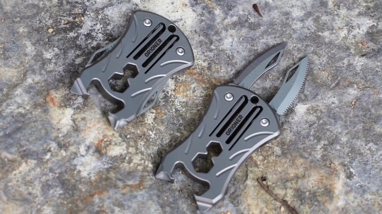 Two compact Orioner multitools on a rock.