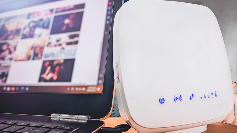 A laptop screen with a network router in the foreground