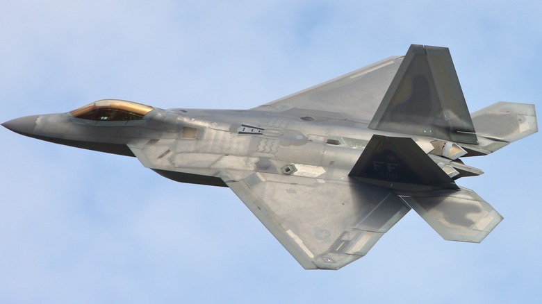 An F-22 Raptor flying over cloudy blue skies
