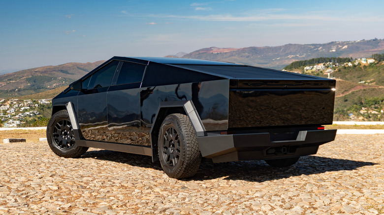 Black Tesla Cybertruck parked on dirt with mountainous terrain in the distance