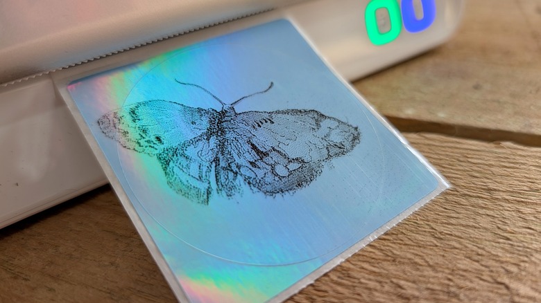 Butterfly sticker near a printer on a wood surface.