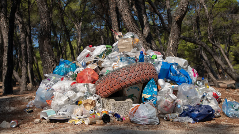 Pile of assorted plastic and rubber garbage with bags and an old tire