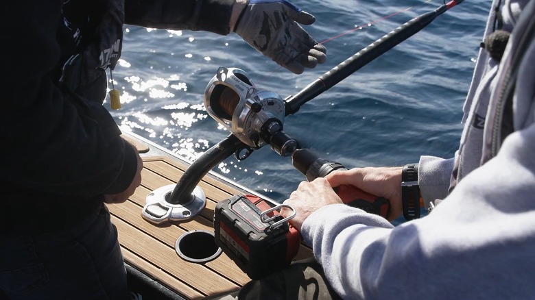 A man using a cordless drill with his fishing reel