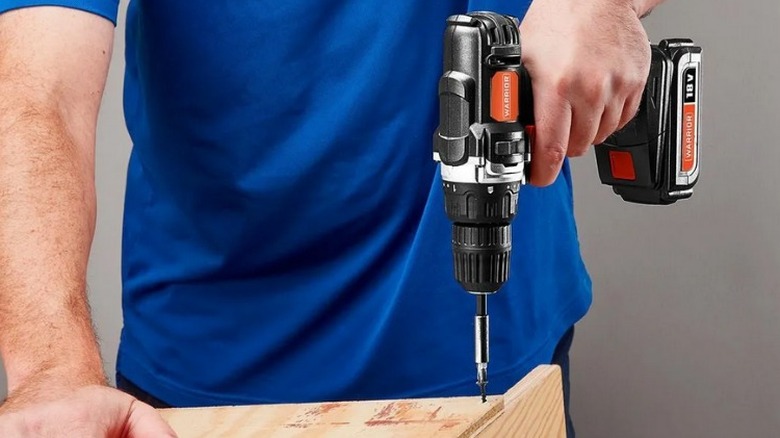 Person driving screw into plywood with Warrior 18V Cordless ⅜-inch Drill