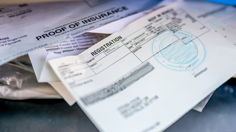 Vehicle insurance and registration documents on a table.