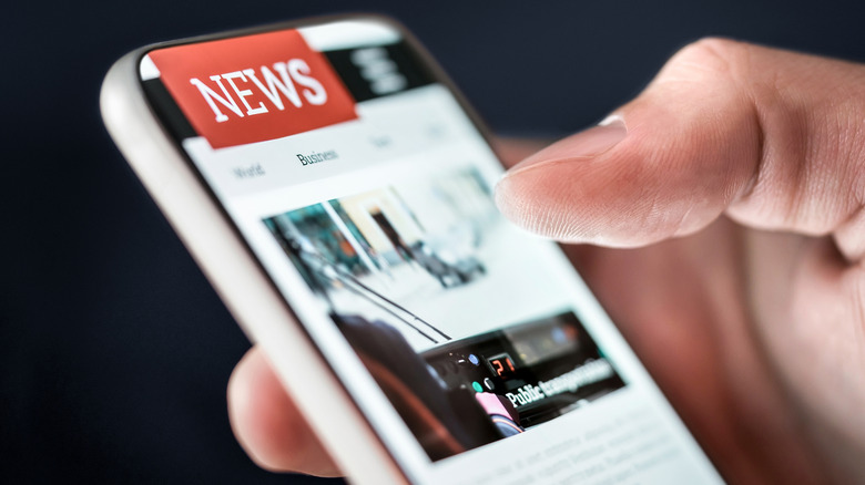 Close up of a hand holding a smartphone showing a News website