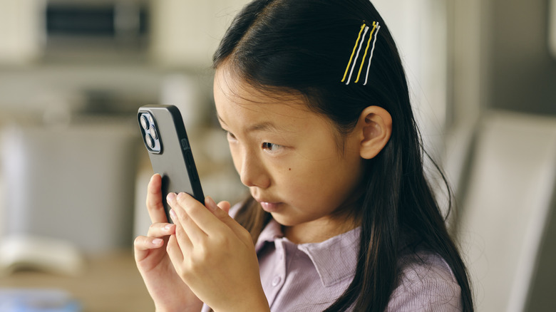 child holding smartphone up to face