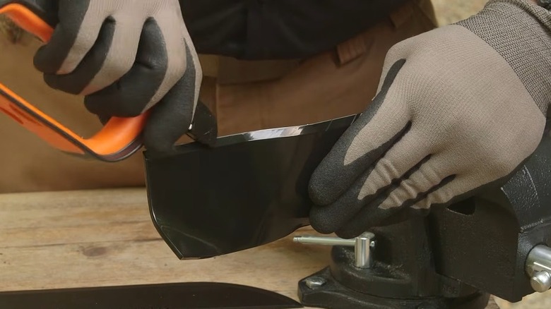 Person's hands using the SHARPAL 103N All-in-1 on a mower blade