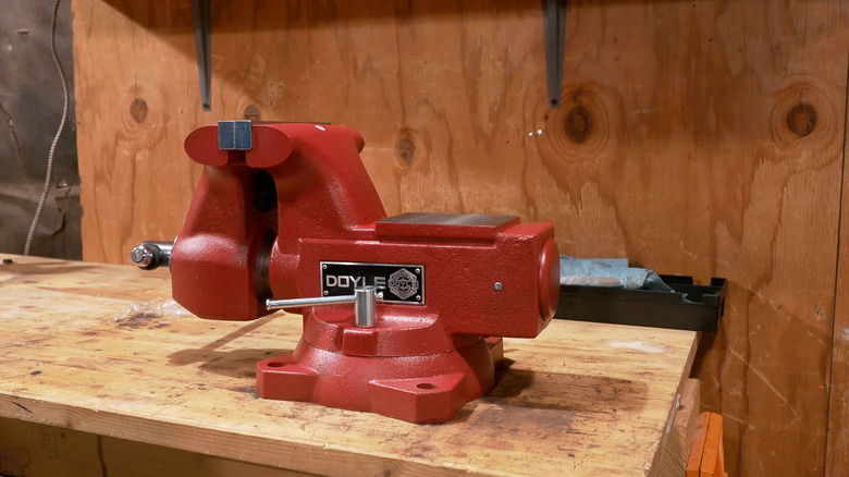 A brand new, freshly unboxed Doyle vise on a wooden workbench, plywood in the background
