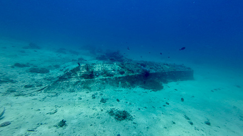 A shipwreck laying on the sand under deep blue water