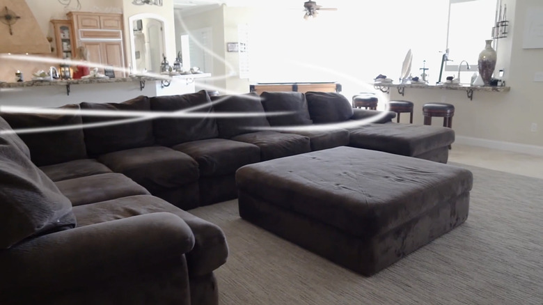 Graphic shows cool air blowing through a living room above brown couches