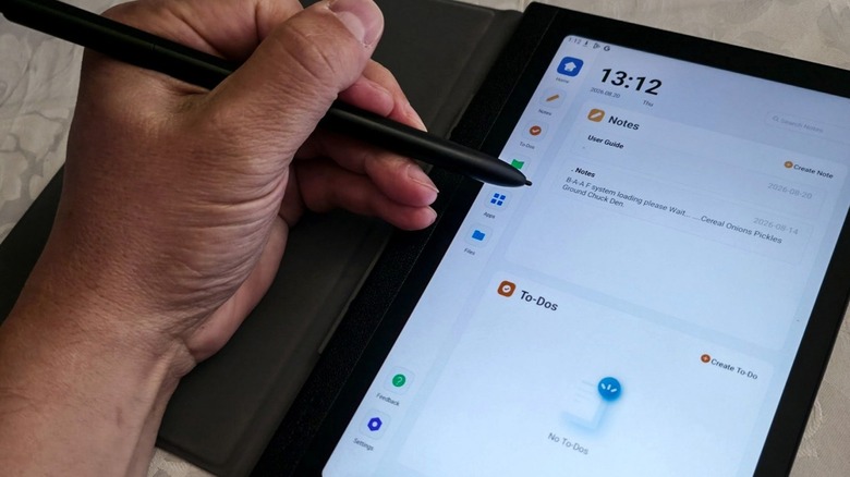 A person holding a stylus while using the Huion Note E tablet