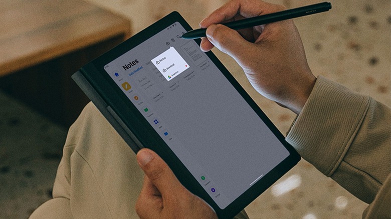 A man holding a Huion Note E while he highlights a portion of the screen with its pen.