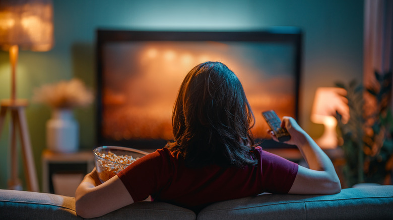 Woman watching the TV and eating popcorn