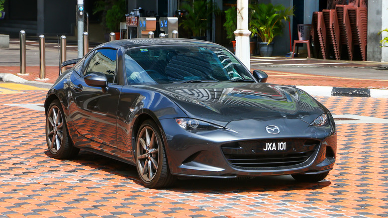 A Mazda MX-5 Miata RF on the move with its roof closed, front 3/4 view, gray exterior