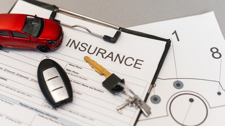 Car keys and insurance documents on a table.