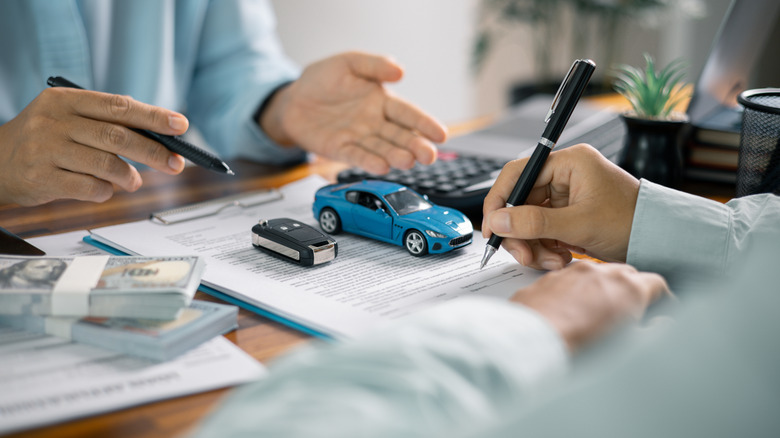 Two people signing auto insurance documents.